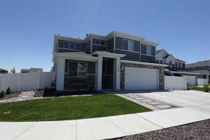 View of front of property with an attached garage, driveway, stone siding, a porch, and a gate