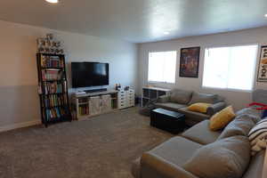 Carpeted living area with plenty of natural light, recessed lighting, baseboards, and a textured ceiling