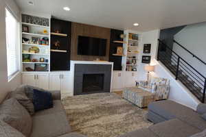 Living room featuring recessed lighting, a glass covered fireplace, wood finished floors, and built in shelves