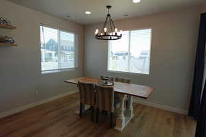 Dining room with a chandelier, baseboards, wood finished floors, and recessed lighting
