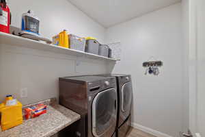 Laundry area featuring washer and clothes dryer, baseboards, and light wood-style floors