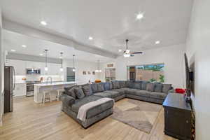 Living area featuring light wood-style floors, ceiling fan, recessed lighting, and a chandelier