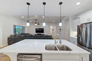 Kitchen featuring appliances with stainless steel finishes, a sink, open floor plan, a kitchen island with sink, and recessed lighting