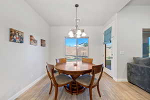 Dining area with a chandelier, light wood-style floors, and baseboards