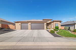 Prairie-style home featuring a garage, driveway, a tile roof, and stucco siding