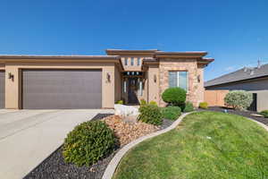 Prairie-style home featuring an attached garage, concrete driveway, stone siding, and stucco siding