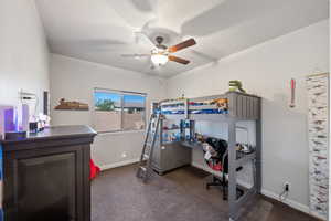 Bedroom with dark colored carpet, baseboards, and a ceiling fan