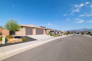 View of asphalt road with sidewalks, a residential view, a mountain view, and curbs