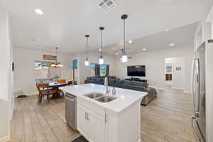 Kitchen featuring stainless steel appliances, a sink, open floor plan, light wood-style flooring, and recessed lighting