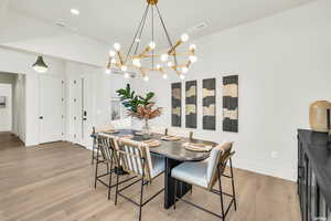Dining room featuring light wood finished floors, a chandelier, and baseboards