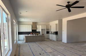 Kitchen with healthy amount of natural light, white cabinets, a center island, backsplash, and a textured ceiling