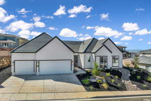 View of front of property featuring a garage, stucco siding, concrete driveway, and a tiled roof