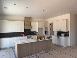 Kitchen with a large island, decorative backsplash, white cabinets, a textured ceiling, and recessed lighting