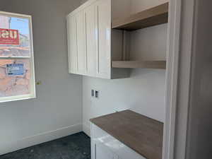 Laundry room with washer hookup, cabinet space, and dark tile patterned floors