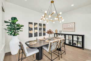 Dining area featuring light wood finished floors, a chandelier, baseboards, vaulted ceiling, and recessed lighting