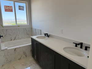 Full bathroom featuring marble finish floors, a bath, and double vanity