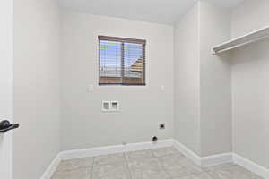 Washroom with washer hookup, electric dryer hookup, baseboards, light tile patterned flooring, and hookup for a gas dryer