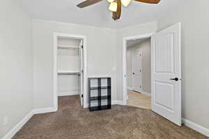 Unfurnished bedroom with carpet flooring, a spacious closet, a closet, a ceiling fan, and baseboards