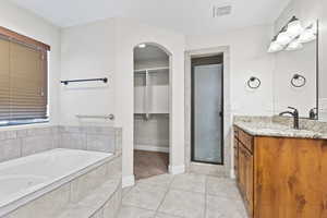 Bathroom featuring a stall shower, vanity, a spacious closet, and a jetted tub
