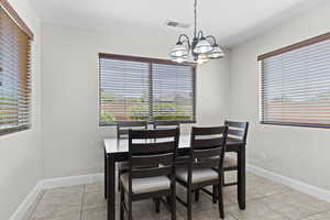 Dining space with a chandelier, plenty of natural light, and light tile patterned floors