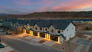 View of front facade featuring a garage, stucco siding, driveway, a mountain view, and a residential view