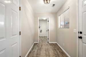 Hall with wood finished floors, baseboards, and a textured ceiling