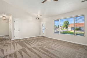 Carpeted spare room featuring a ceiling fan, lofted ceiling, and baseboards