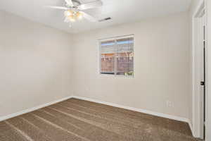 Empty room with dark colored carpet, baseboards, and a ceiling fan