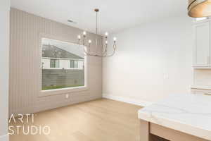 Dining space with light wood finished floors, baseboards, and a chandelier