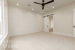 Unfurnished bedroom with carpet, recessed lighting, a barn door, ceiling fan, and baseboards