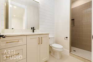 Full bath with toilet, vanity, tiled shower, and tile patterned floors
