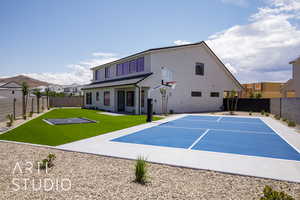 Rear view of property featuring basketball court, stucco siding, and uncovered parking