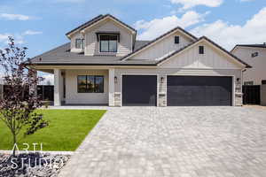 View of front of home with decorative driveway, a tile roof, an attached garage, and board and batten siding