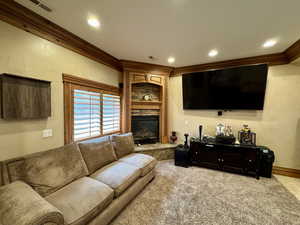Living room with crown molding, a fireplace, light colored carpet, recessed lighting, and baseboards