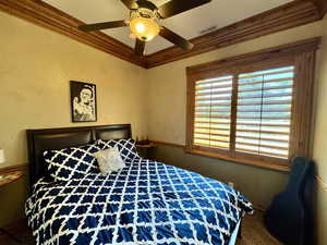 Carpeted bedroom with crown molding and ceiling fan