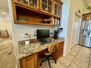 Office space featuring built in desk, baseboards, and light tile patterned flooring