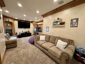 Living area with ornamental molding, carpet flooring, recessed lighting, and a fireplace