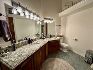 Full bathroom with toilet, vanity, baseboards, and tile patterned flooring