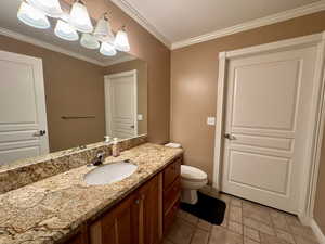 Bathroom with vanity, crown molding, toilet, baseboards, and tile patterned flooring