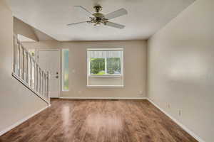 Entrance foyer with wood finished floors, baseboards, stairway, and a textured ceiling