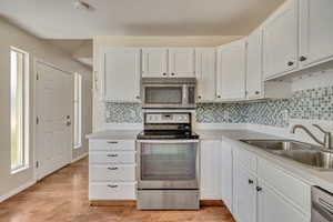 Kitchen featuring appliances with stainless steel finishes, a sink, plenty of natural light, and white cabinetry