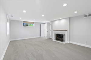 Unfurnished living room with recessed lighting, carpet flooring, baseboards, and a fireplace with flush hearth