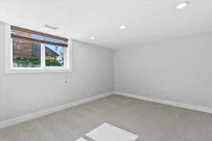 Empty room featuring light colored carpet, baseboards, and recessed lighting