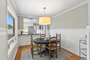 Dining room featuring wainscoting, wood finished floors, and crown molding