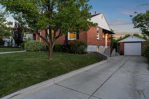 Obstructed view of property with brick siding, an outdoor structure, driveway, a front lawn, and a garage