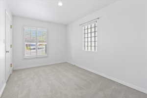 Spare room with baseboards, light carpet, and recessed lighting