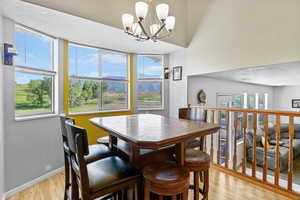 Dining space featuring light wood finished floors, a chandelier, baseboards, and a textured ceiling