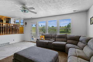 Living room featuring a ceiling fan, a textured ceiling, and baseboards