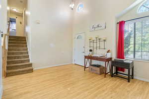 Entryway featuring healthy amount of natural light, wood finished floors, stairs, and a high ceiling
