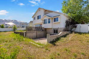 Back of house with a fenced backyard and a mountain view